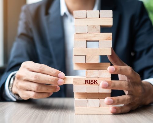 Businessman hand placing or pulling wooden block on the tower. Business planning, Risk Management, Solution and strategy Concepts