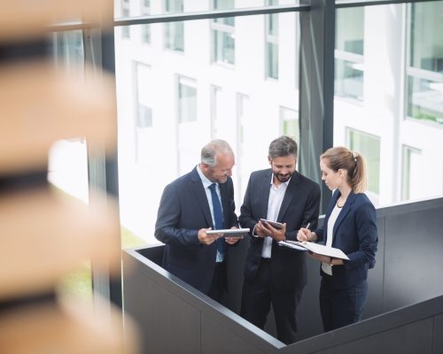Group of businesspeople having a discussion near staircase in office