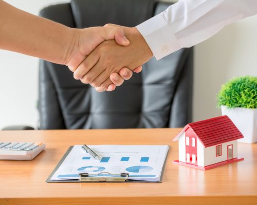 Side view hands of agent and client shaking hands after signed contract buy new apartment.